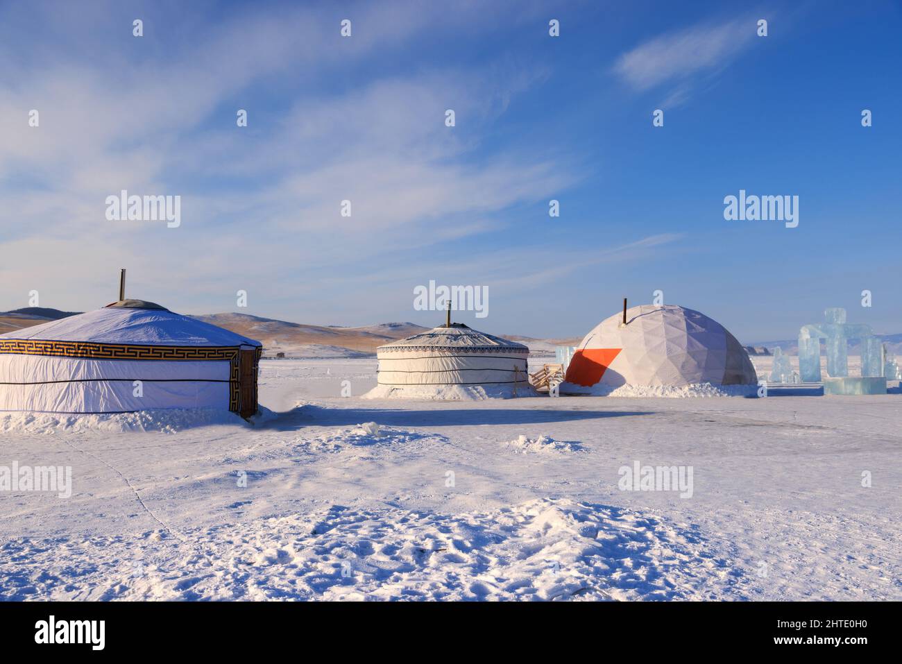Mongolian traditional yurt in a snowy desert with mountains in the background Stock Photo