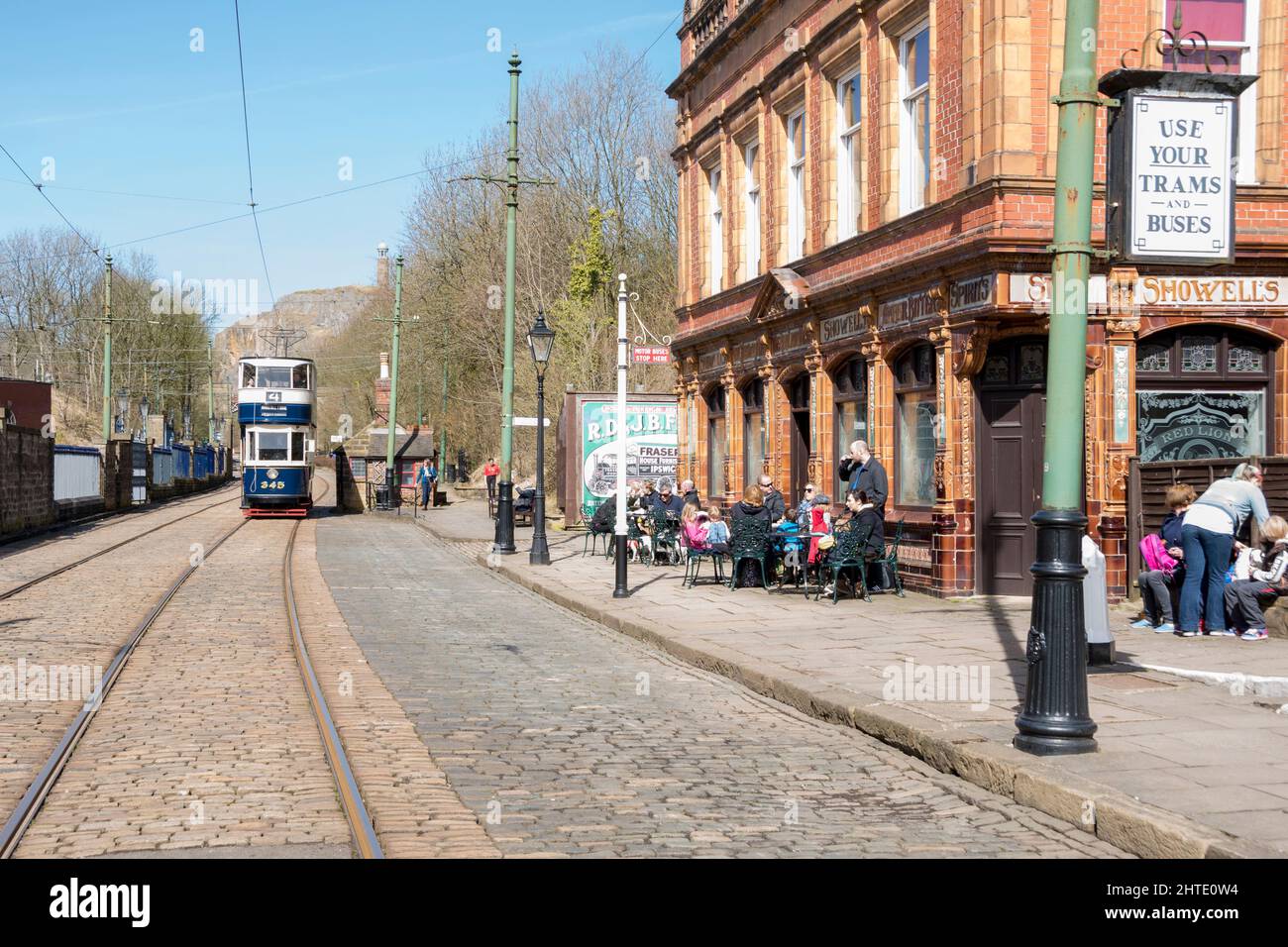 Derbyshire, UK – 5 April 2018: The 345 working vintage tram approaches the Red Lion public house at Crich Tramway Village National Tram Museum Stock Photo