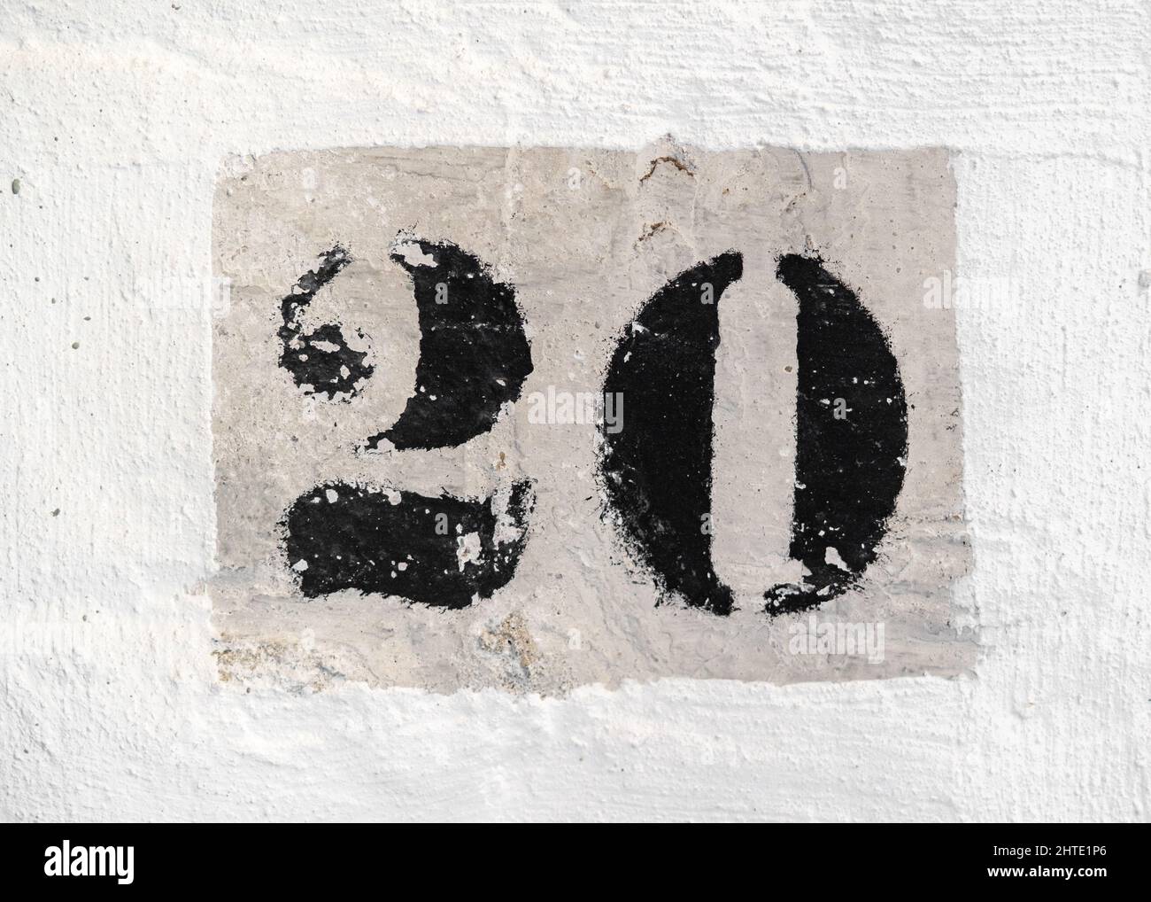 Number 20 retro printed in black paint on a white brick wall. Stock Photo