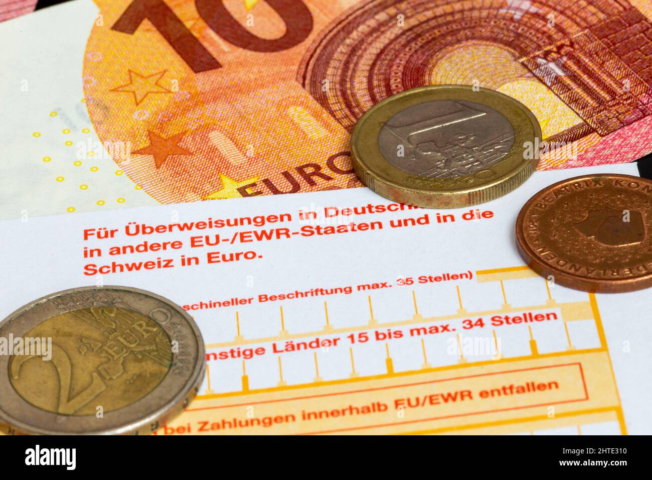 Symbol image payment transactions: Close-up of a bank transfer slip with Euro coins and Euro notes Stock Photo