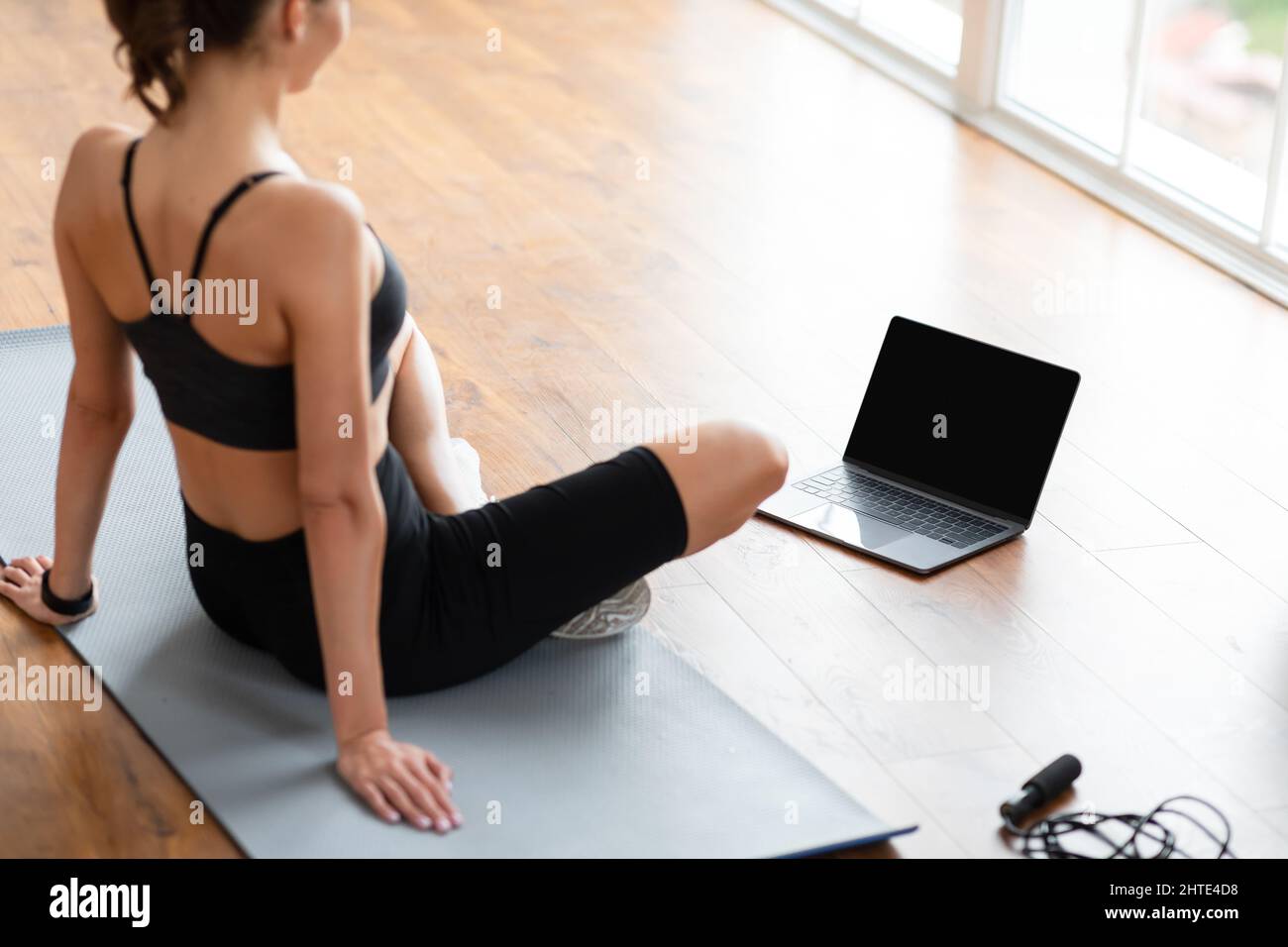 Young black woman sitting on mat with blank pc Stock Photo