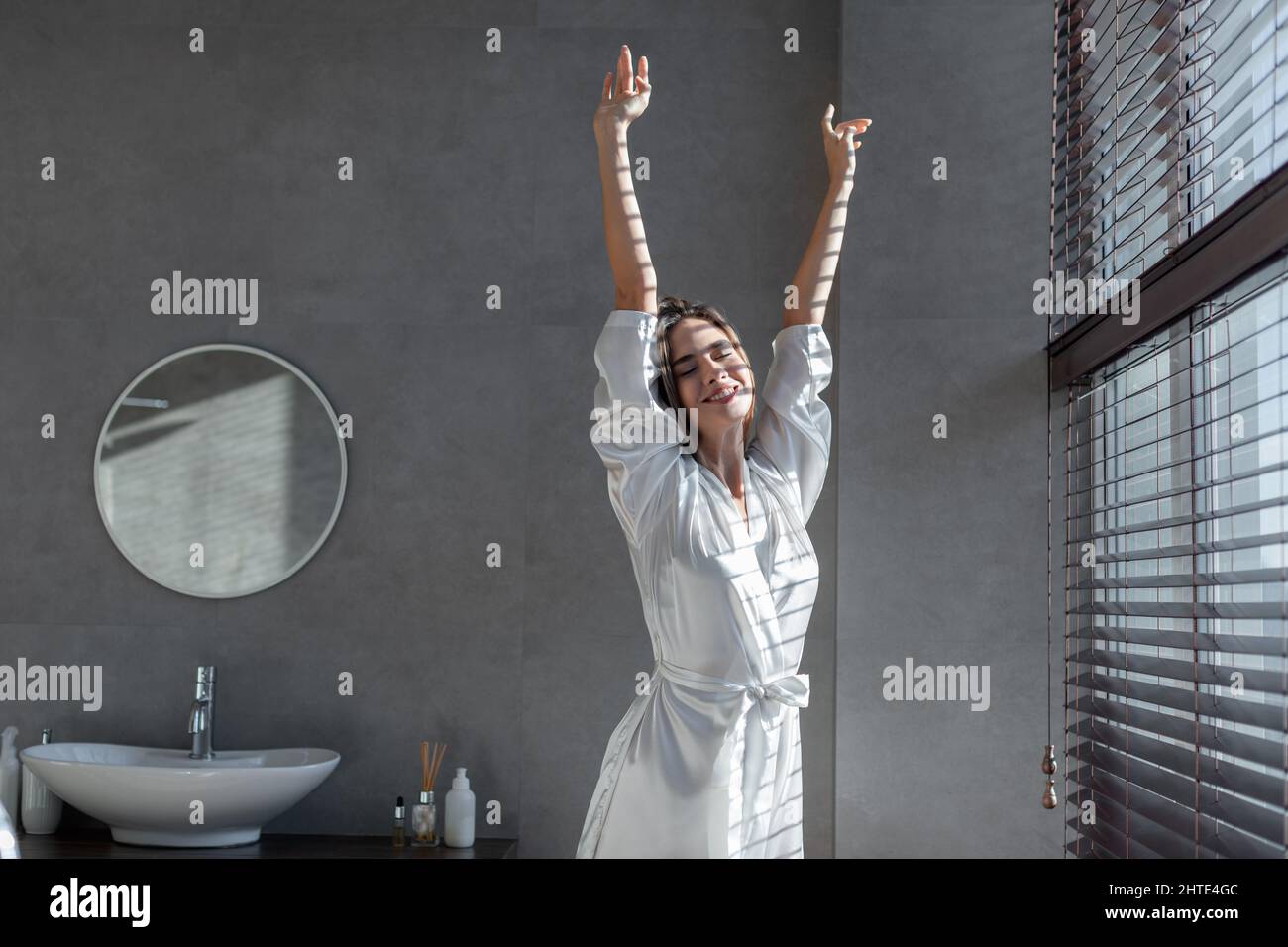 Beautiful Young Woman Wearing White Silk Robe Stretching In Modern Bathroom Stock Photo Alamy