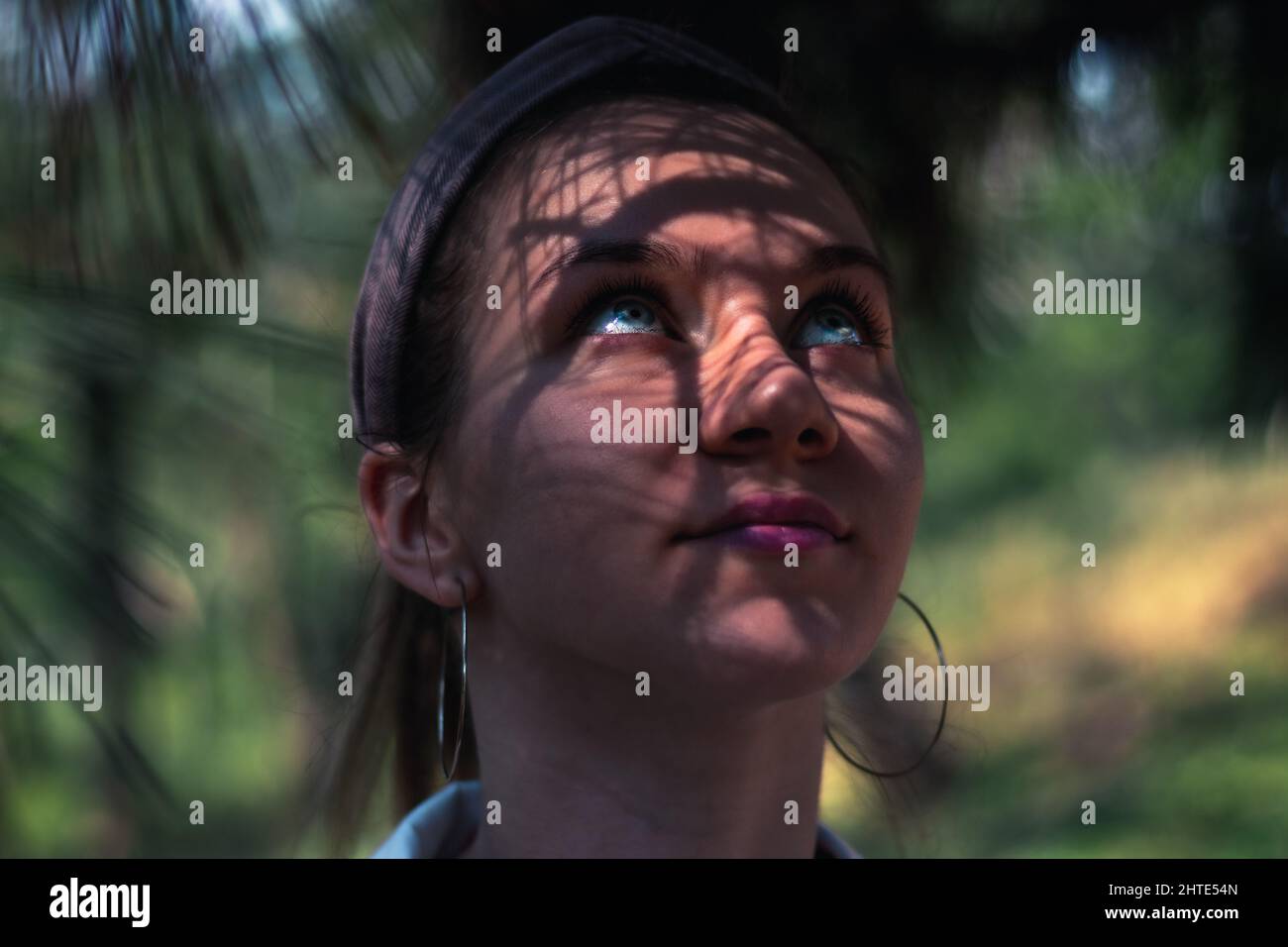 Beautiful Caucasian woman with blue eyes under shadow leaves Stock