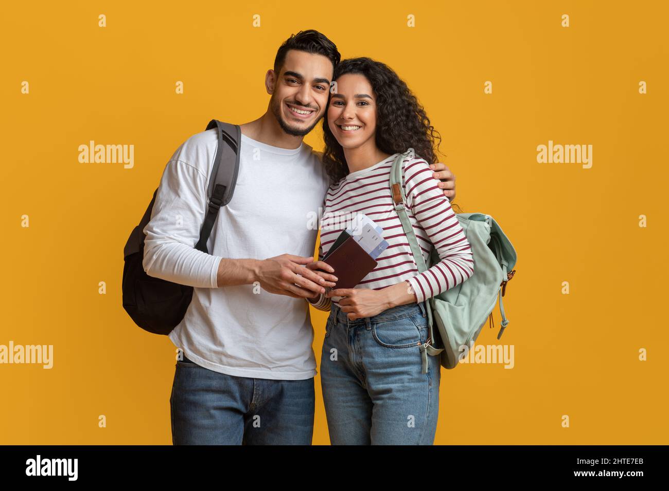 Portrait Of Smiling Arab Travellers Couple With Backpacks, Passports And Tickets Stock Photo