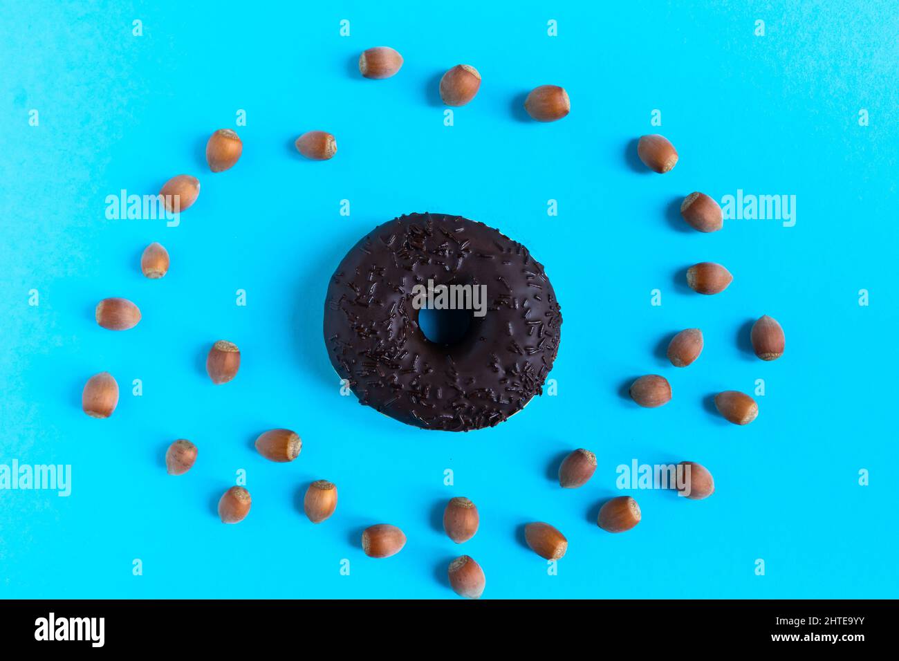 Donut with hazelnuts on a blue background, close up Stock Photo