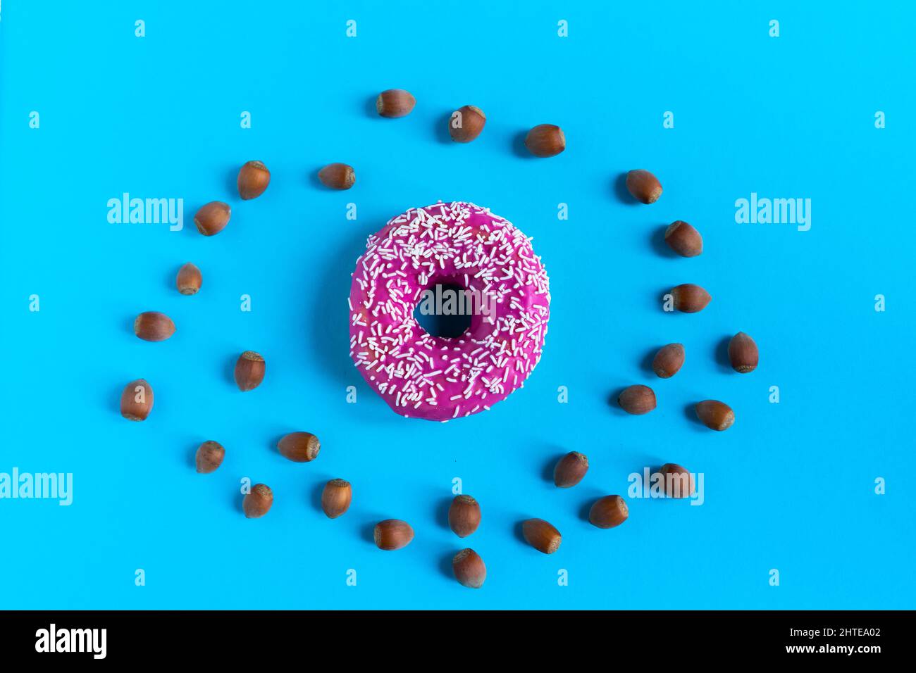 Donut with hazelnuts on a blue background, close up Stock Photo
