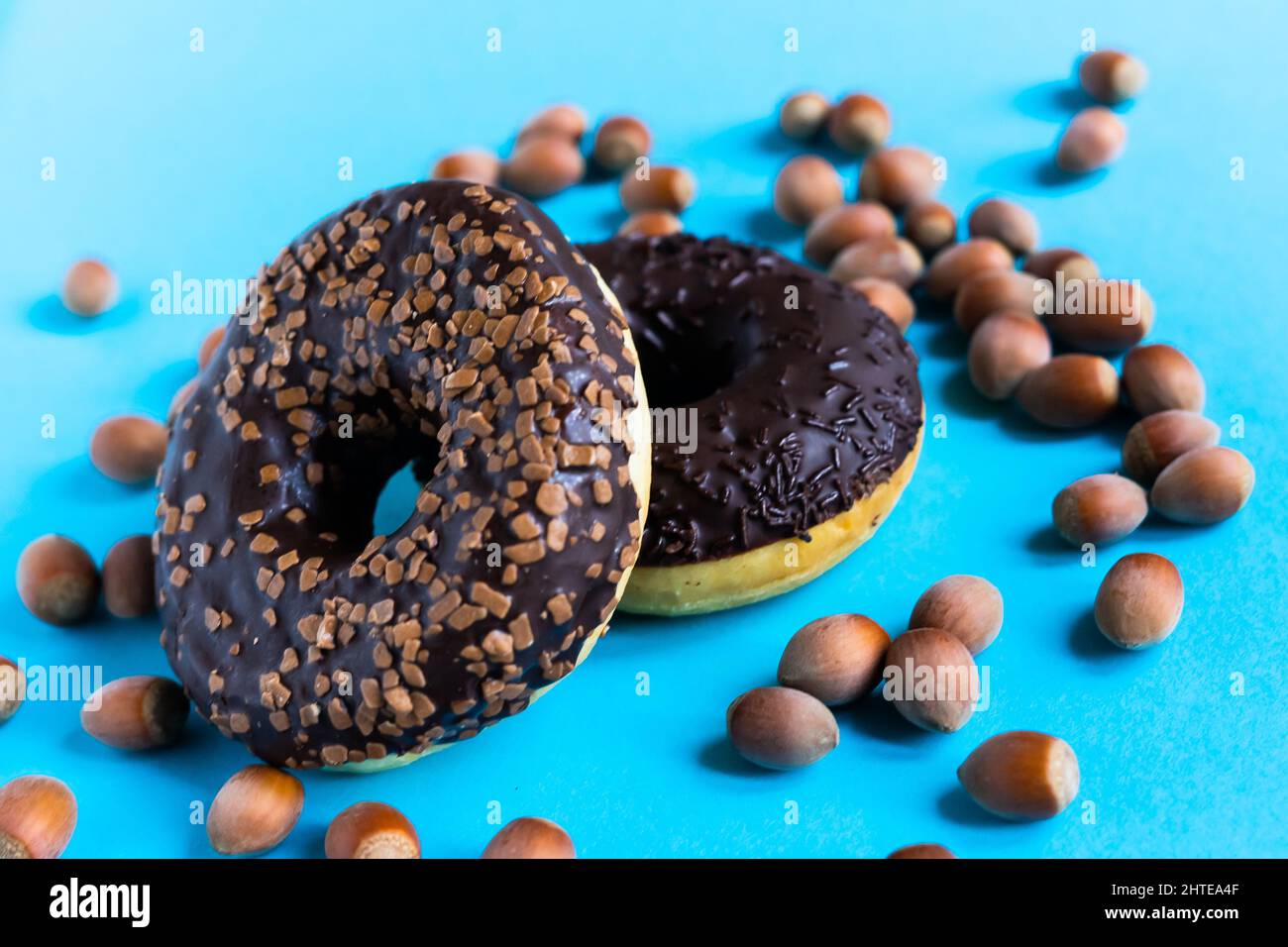 Donut with hazelnuts on a blue background, close up Stock Photo