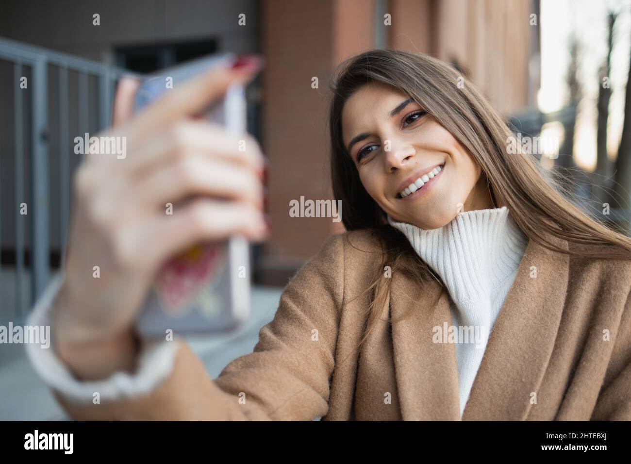 Joyful young woman taking selfie on smartphone in the street Stock ...