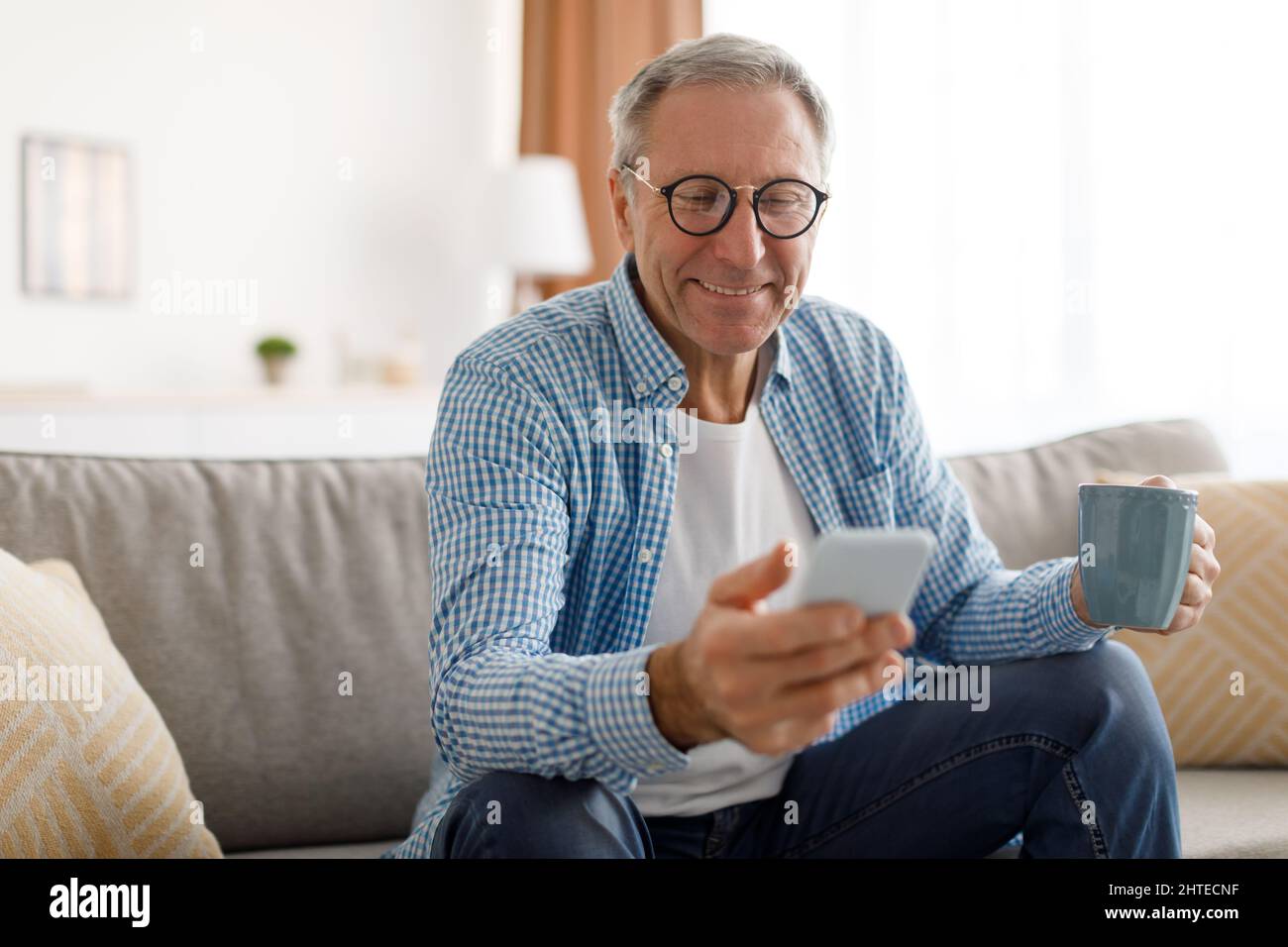 Portrait of smiling mature man using smartphone at home Stock Photo