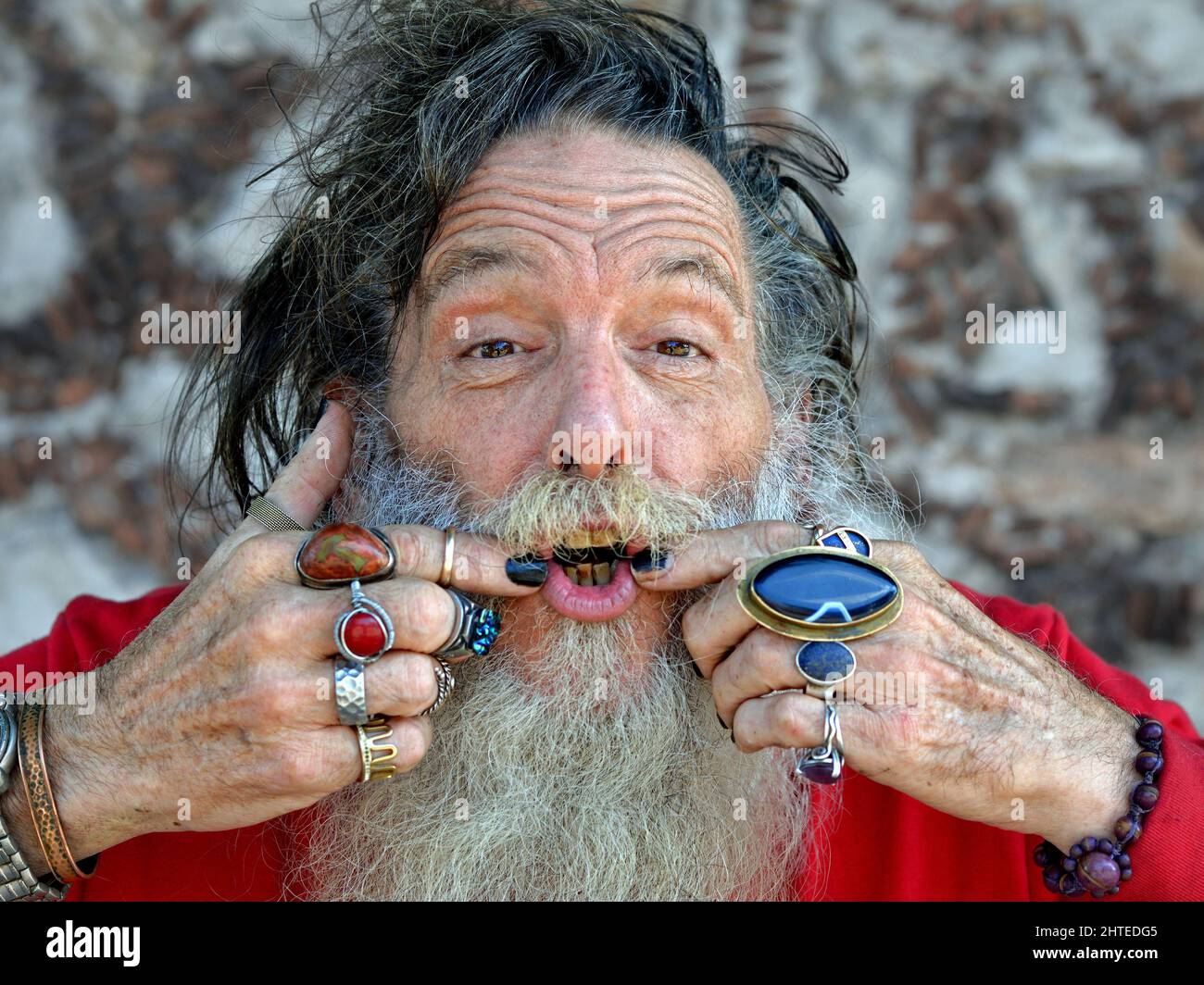 Old Caucasian man shows his mouth and expresses an optimistic talk-the-positive alternative to the negative talk-no-evil of the Three Wise Monkeys. Stock Photo