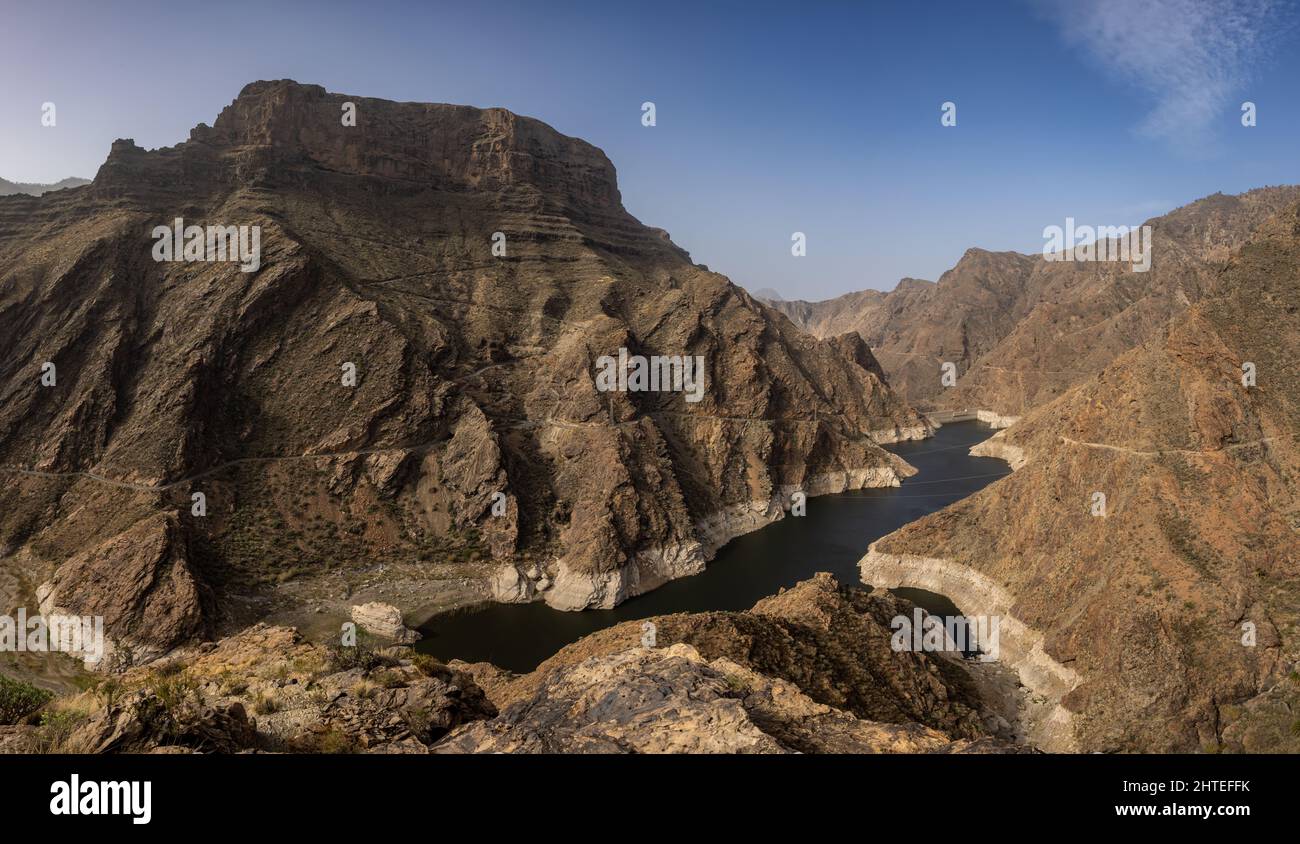 the remote lake presa del paralillo in gran canaria surrounded by an imposing mountain and rugged rocky ridges Stock Photo