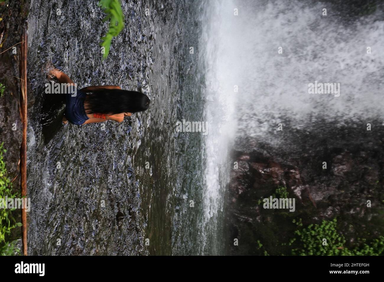 Girl sitting on a lakeshore in front of a waterfall Stock Photo - Alamy