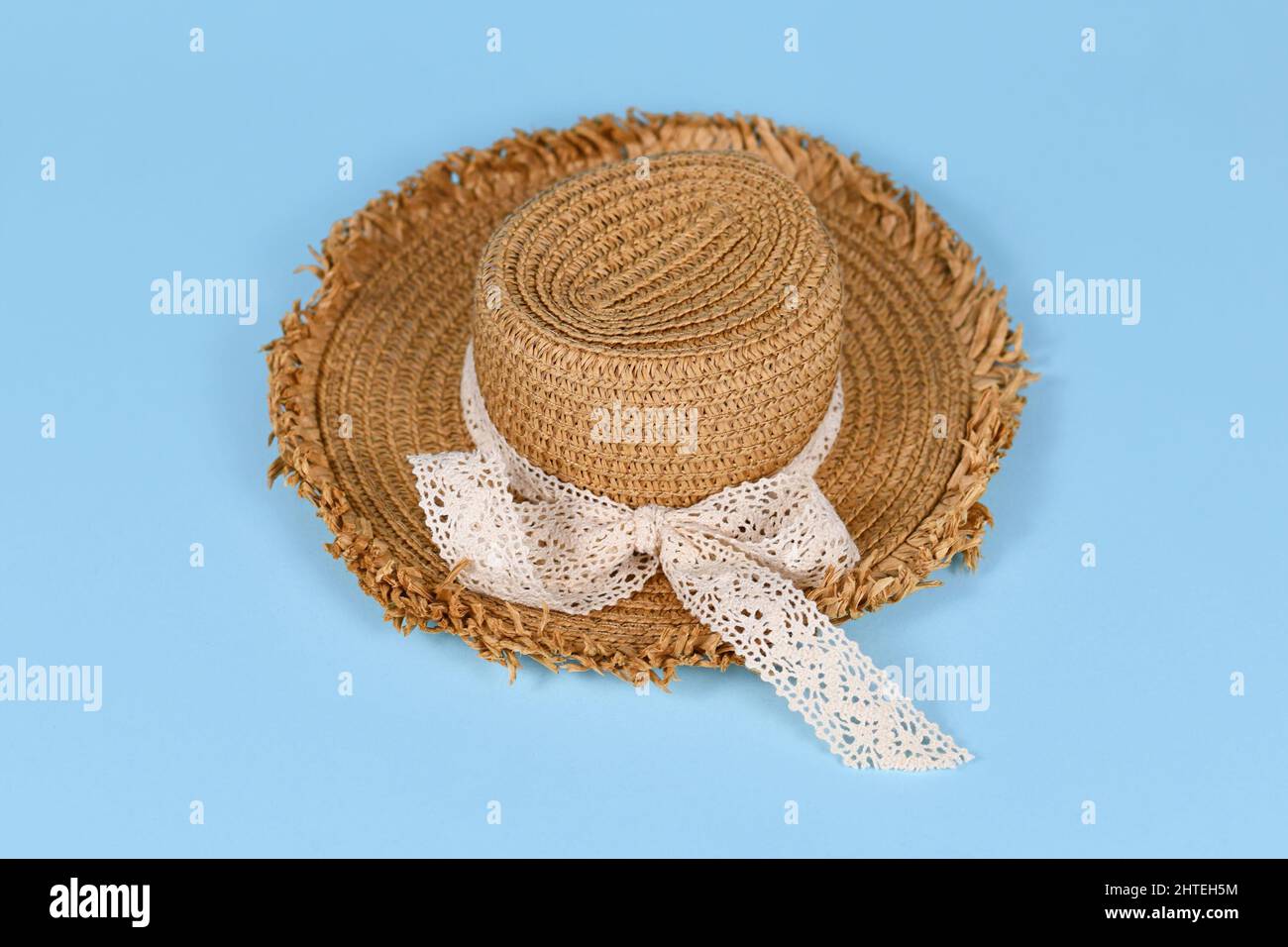 Summer straw hat with lace ribbon on blue background Stock Photo