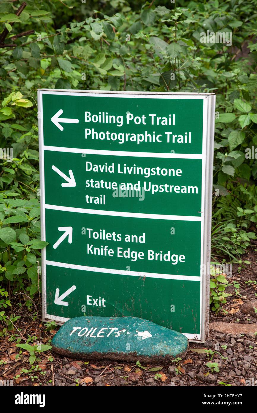 Sign at Mosi-oa-Tunya (Victoria Falls) giving directions to various trails, the Knife Edge Bridge, Toilets, and the exit. Stock Photo