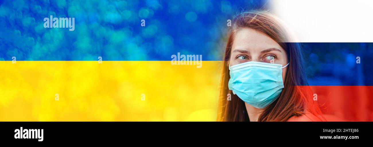 War in Ukraine. Sad caucasian 20s woman in a protective medical mask against blue and yellow ukrainian flag and Russian flag background Stock Photo