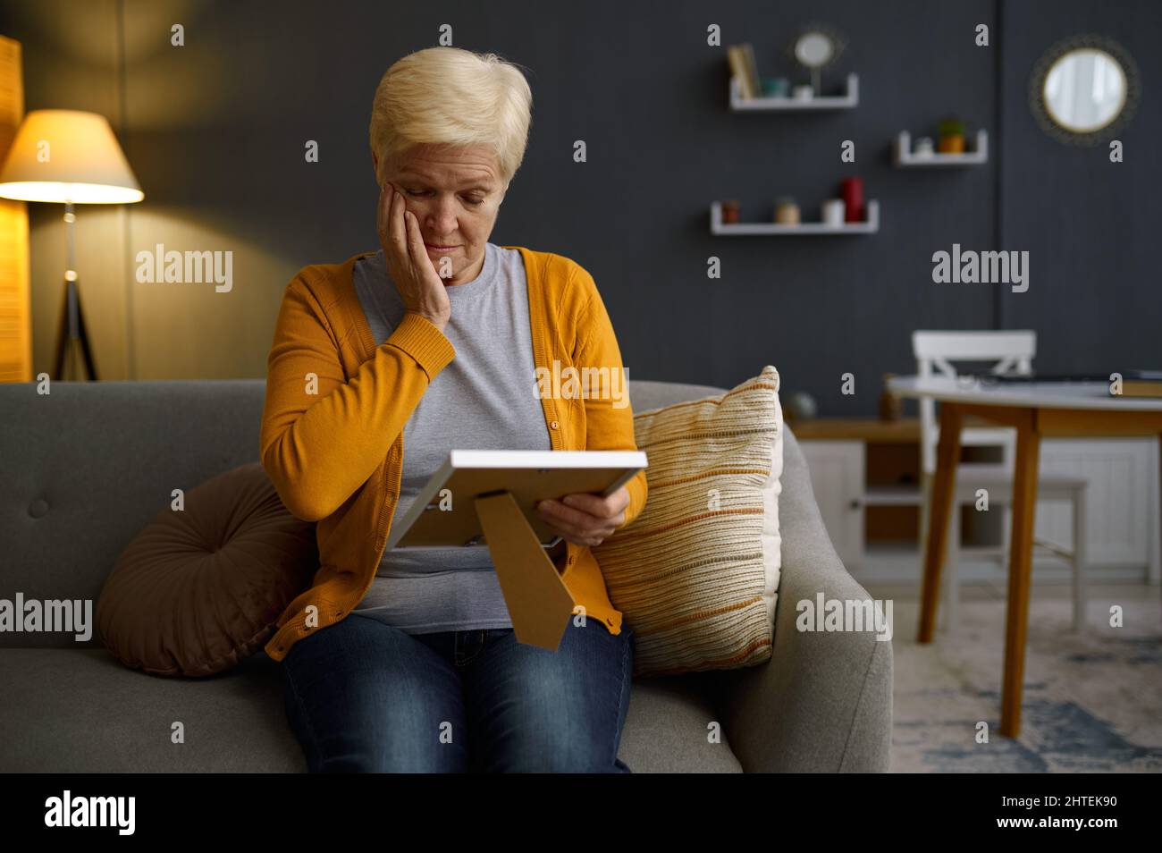 Elderly woman with photo frame at home Stock Photo