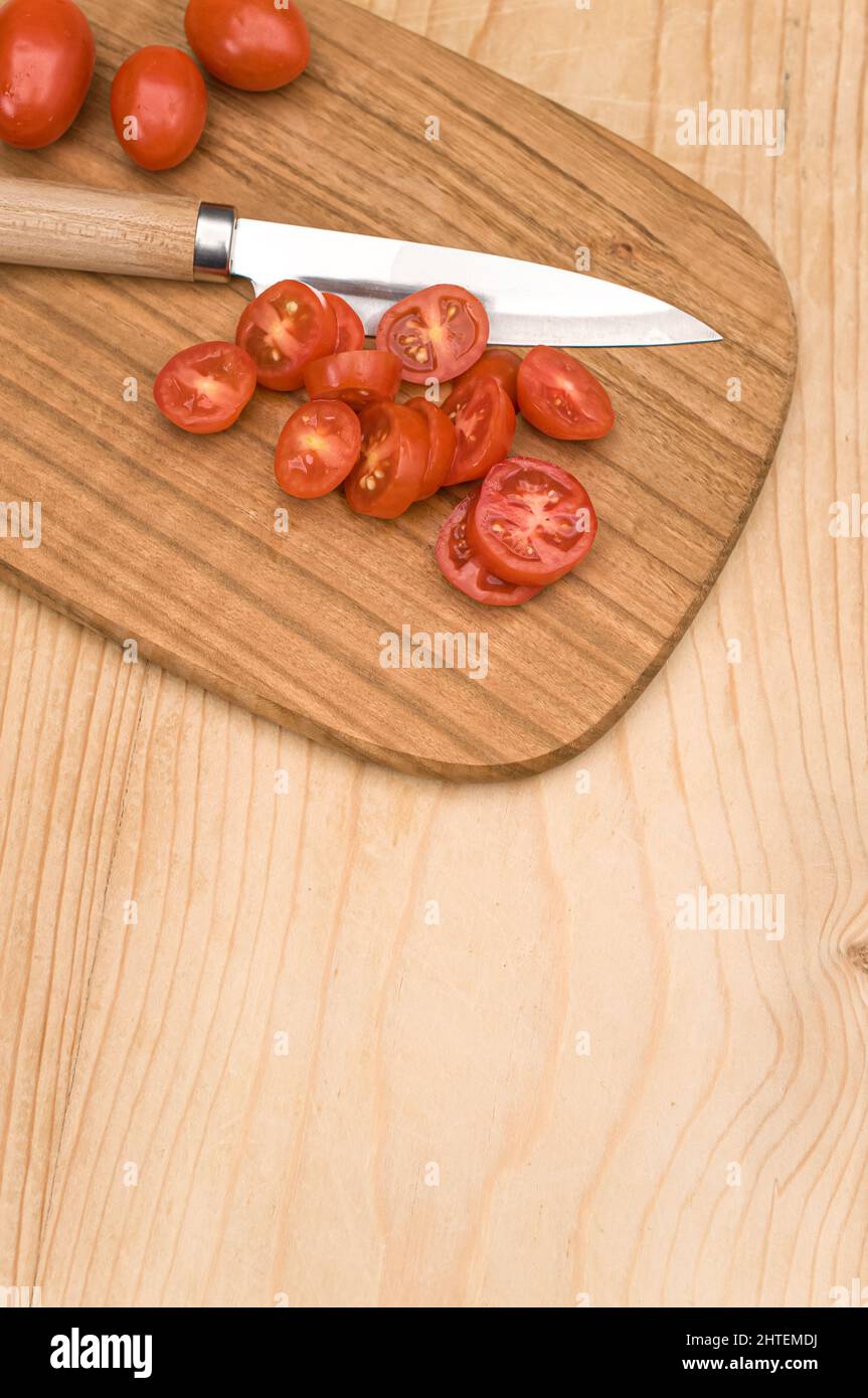 datterini tomatoes and knife on a wooden chopping board on a rustic ...