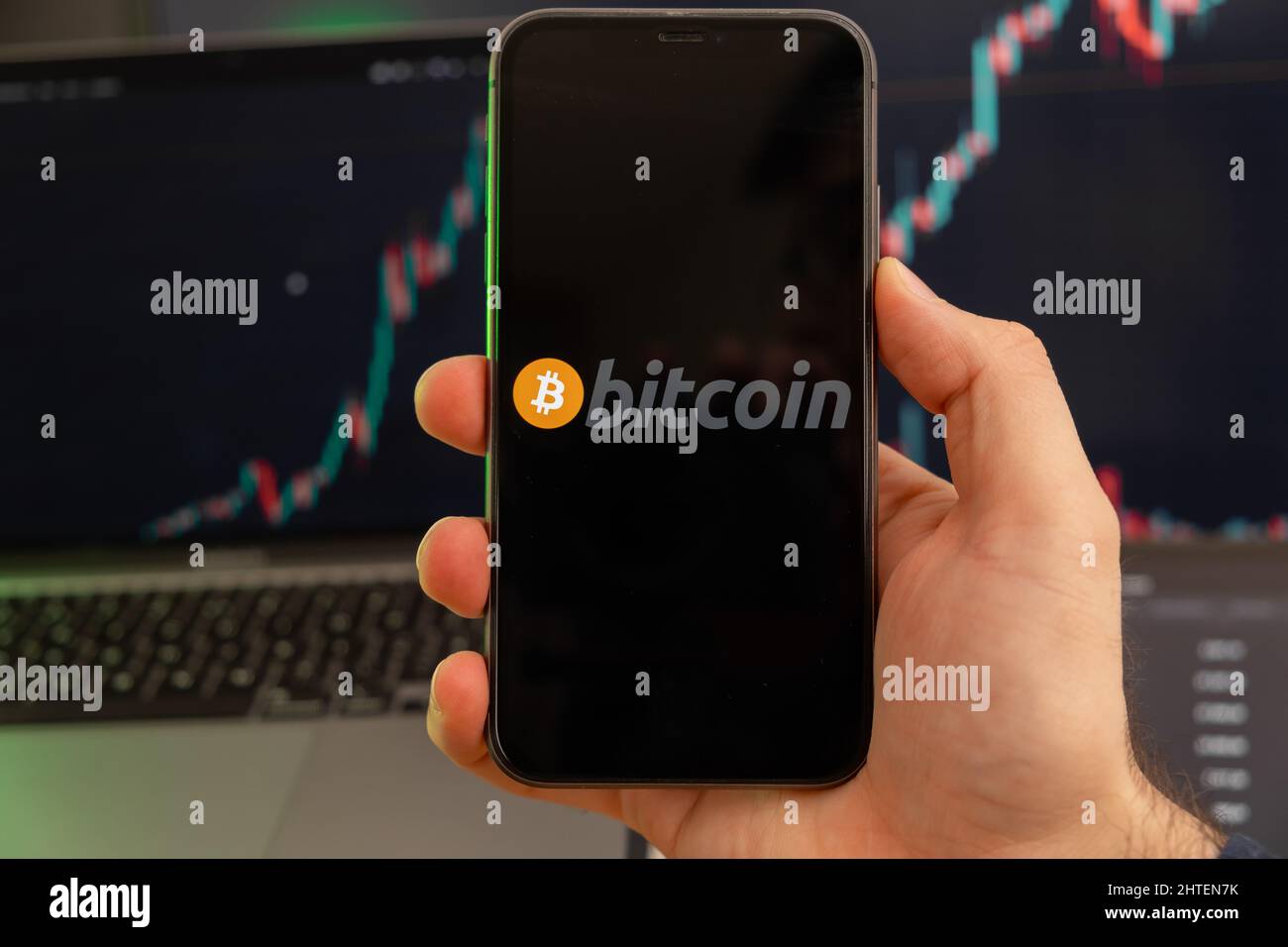 Bitcoin BTC app of cryptocurrency stock market analysis on the screen of mobile phone in man hands and growing charts trading data on the background, February 2022, San Francisco, USA.  Stock Photo
