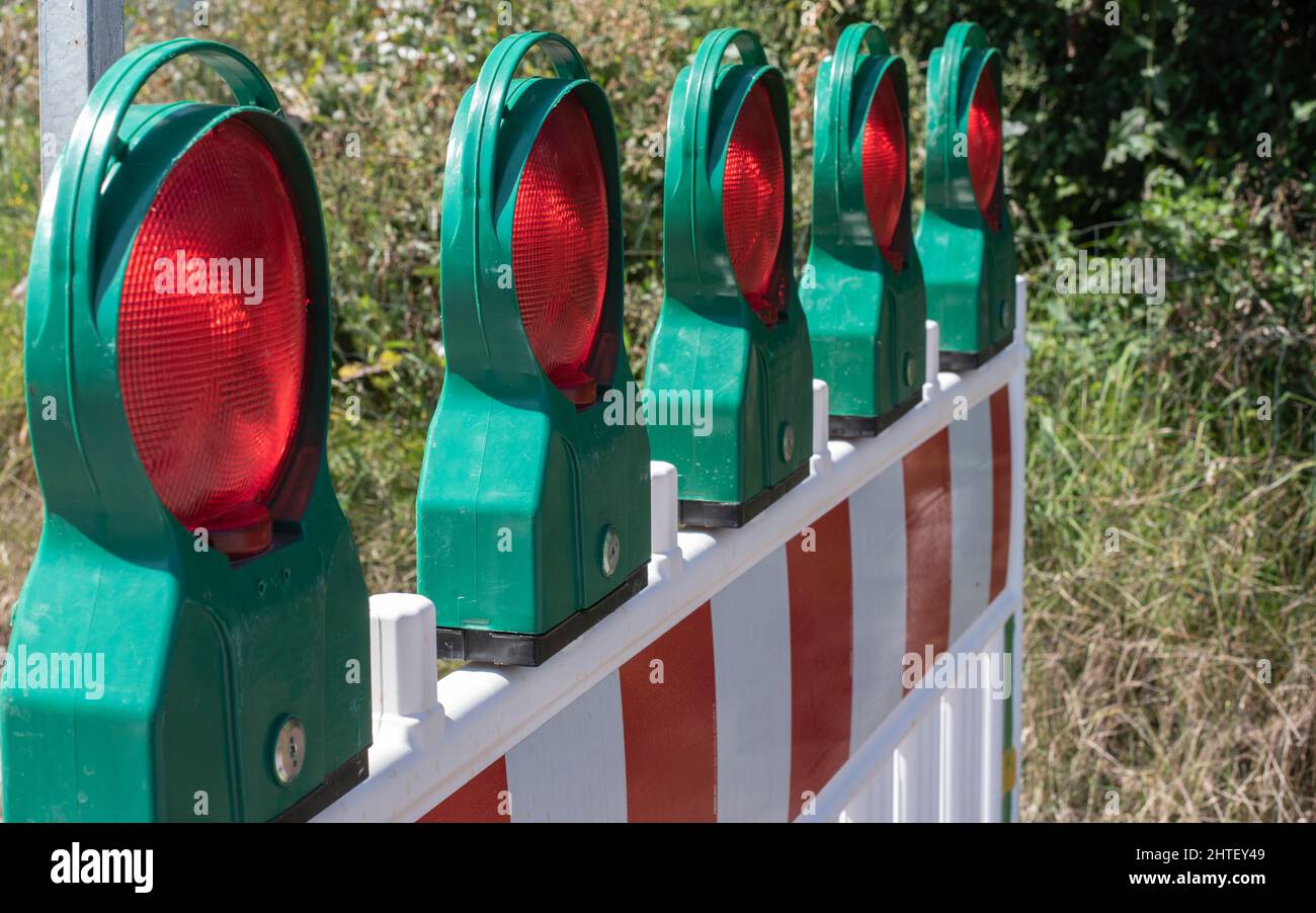 a construction barrier at a road with red reflecting lamps as safety