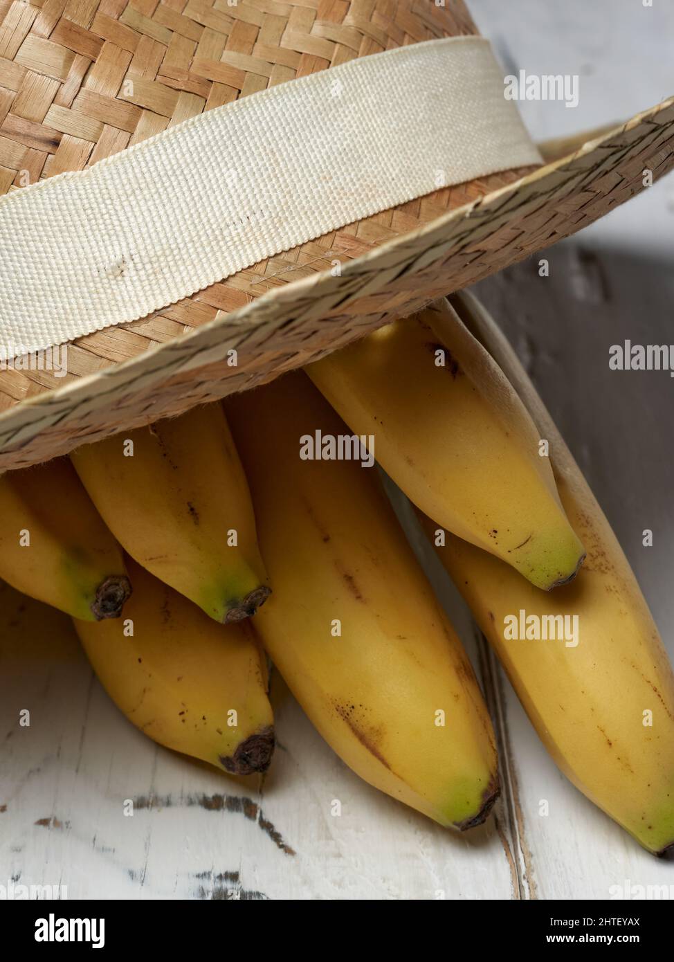 Vertical closeup photo of a bunch of bananas and a straw hat on a wooden table Stock Photo Alamy