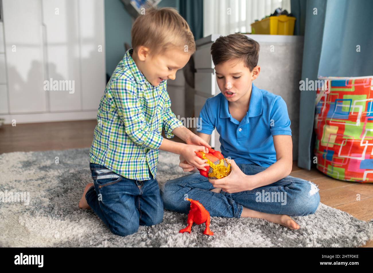 Two kids with rubber animal figures sitting in a room Stock Photo