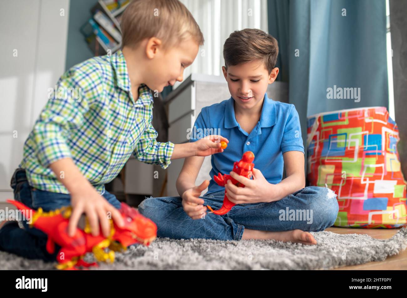 Two children playing with rubber animal figures Stock Photo
