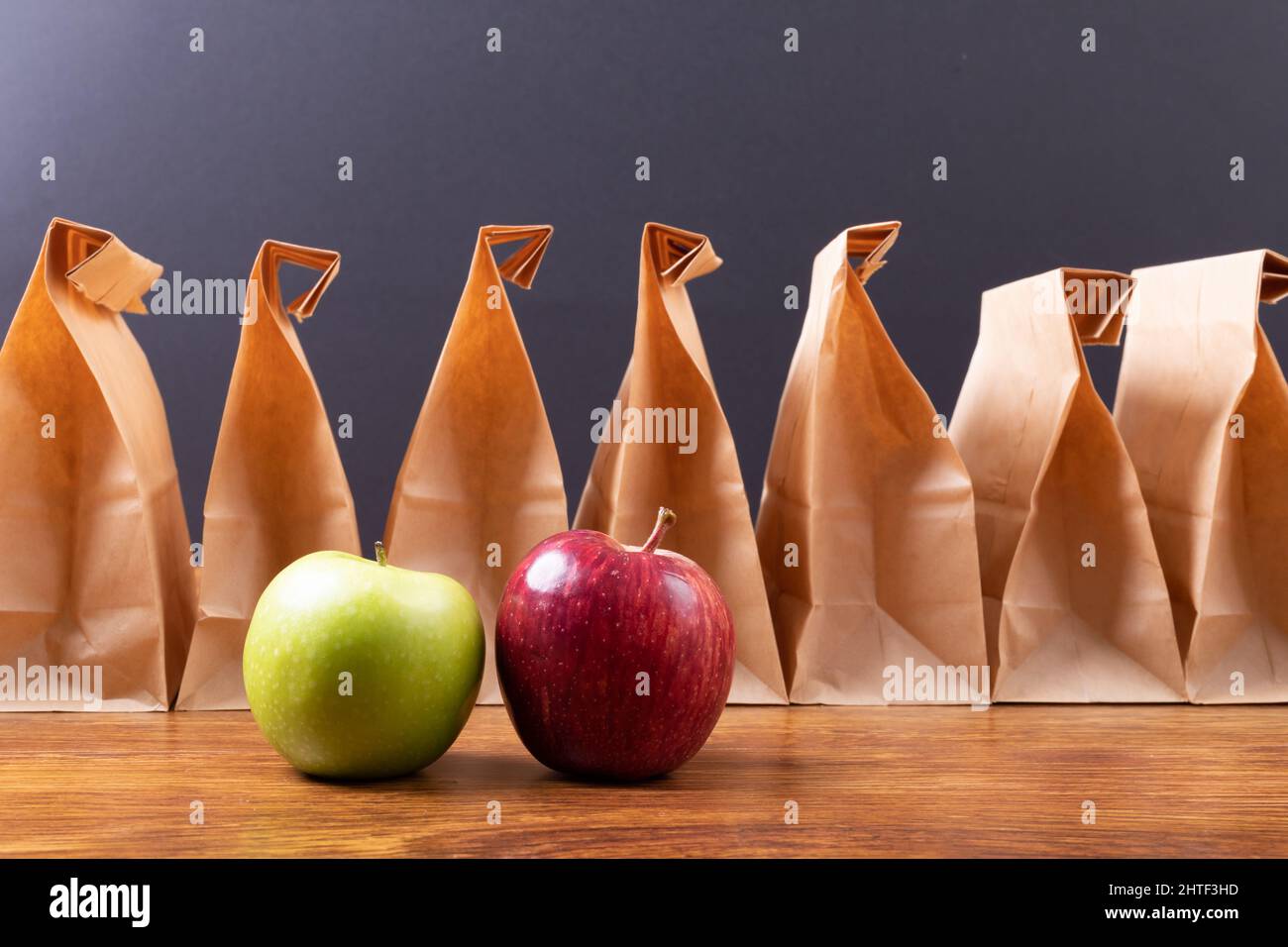 Granny smith apple and apple by paper lunch bags arranged on table against black background Stock Photo