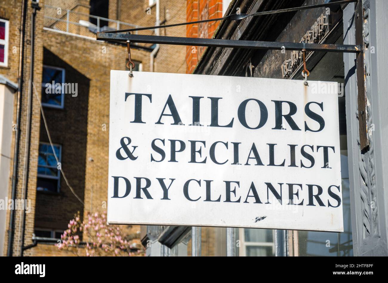 A sign hanging outside a tailors and dry cleaners shop in Earl's Court, London Stock Photo
