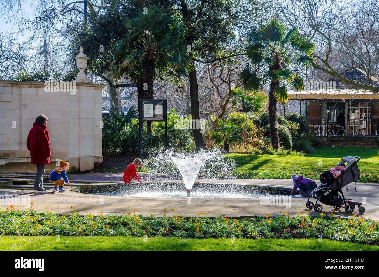 A young family explore the fountain in The London Memorial Gardens. Stock Photo