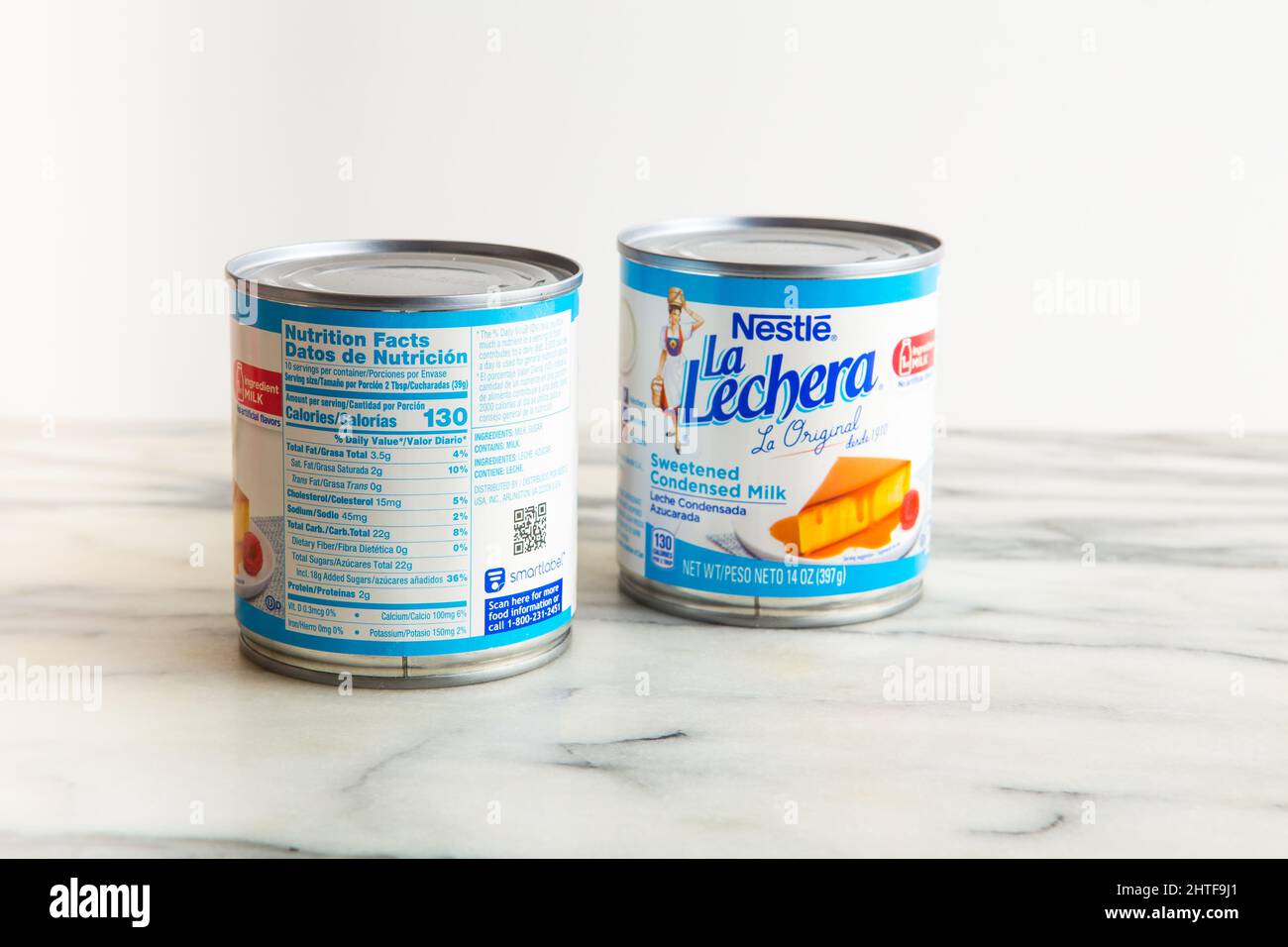 2 tins of Nestle La Lechera sweetened condensed milk showing front and back nutrition facts also known as evaporated milk. Stock Photo