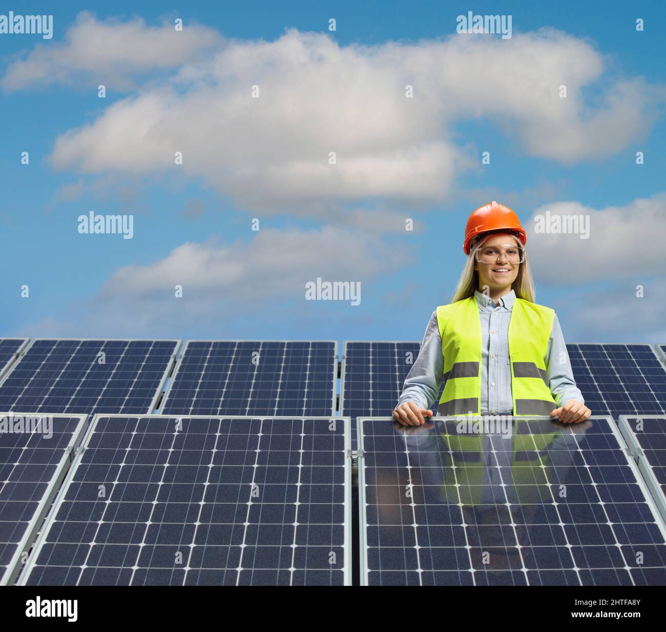 Young female engineer posing between solar panels and smiling Stock Photo