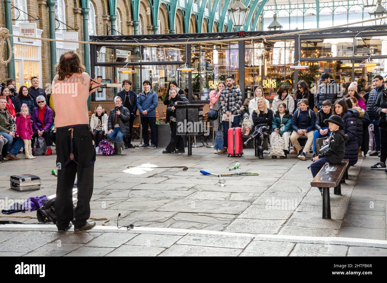 A crowd watch a street performer in he South Hall at Covent Garden in London, UK Stock Photo