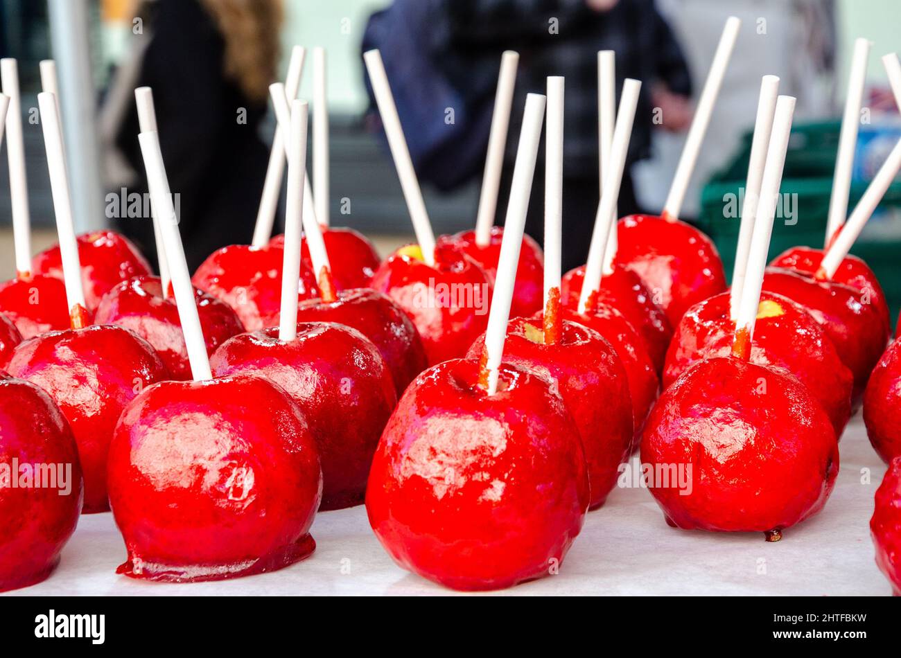 Red toffee apples on sticks on sale in a market Stock Photo