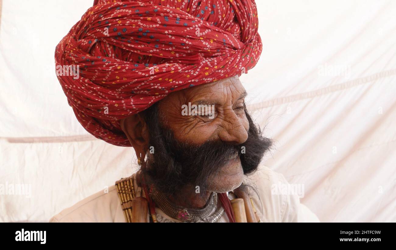 Closeup of an old Indian man with a thick mustache smiling while wearing a pagri Stock Photo