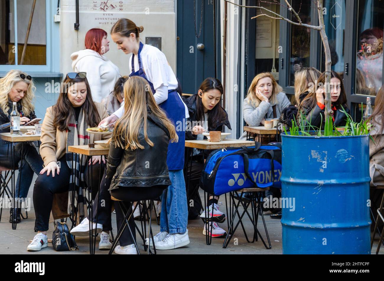 People eating outside at a cafe in Neal's Yard near Covent Garden in London, UK. Stock Photo