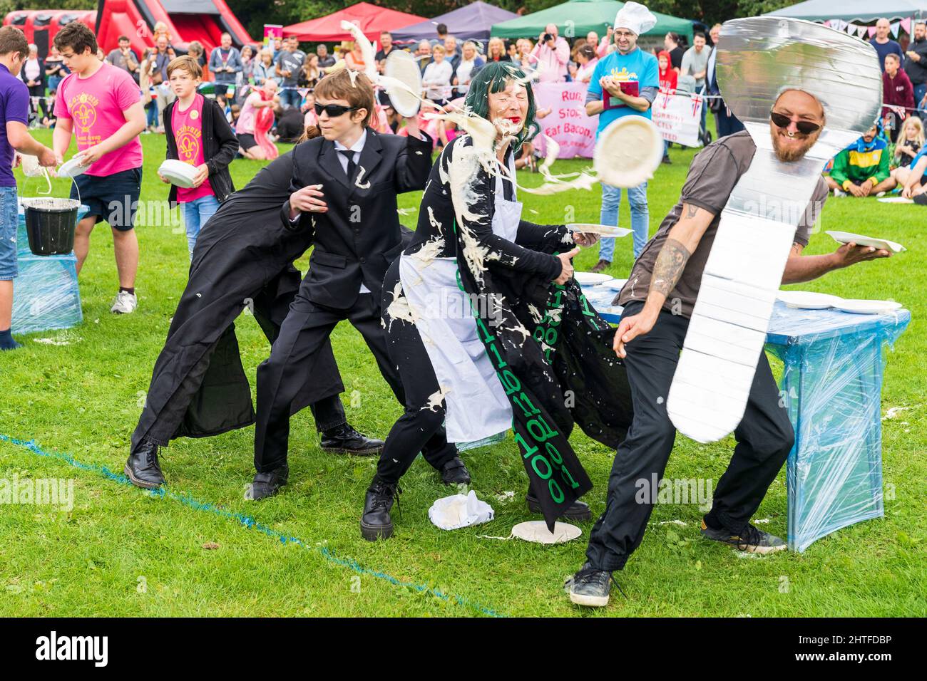 Team of four people in fancy dress, outdoors with table behind them