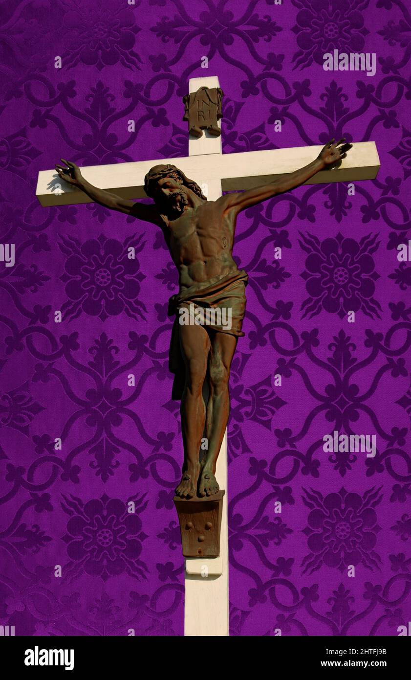 Sun shining on white wood cross with Jesus on Purple silk church parament Stock Photo