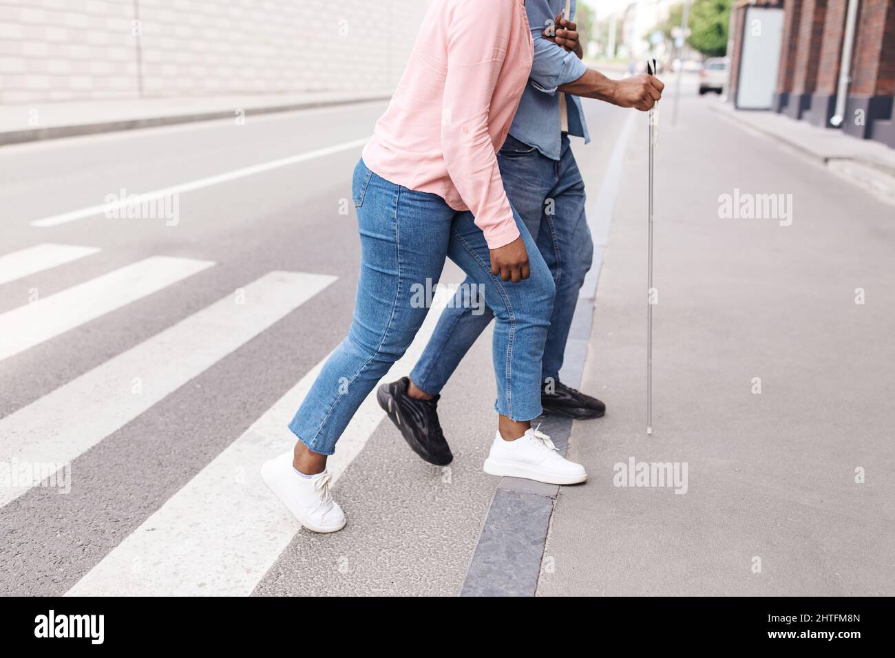 Unrecognizable young black woman assisting millennial guy with vision disability to cross city street, copy space Stock Photo