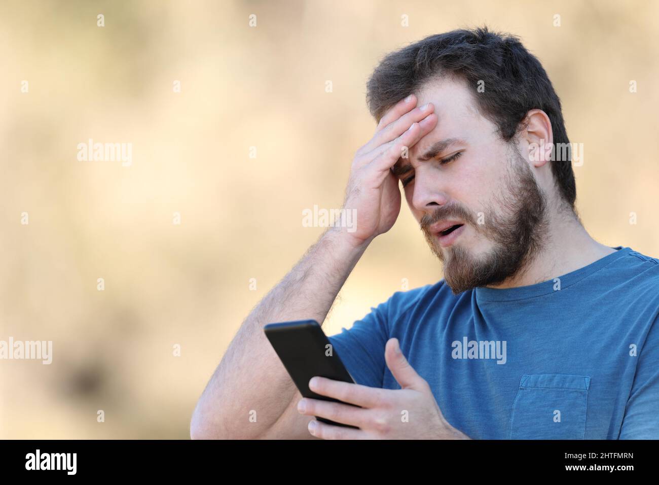 Worried man complaining looking at smart phone after mistake Stock Photo