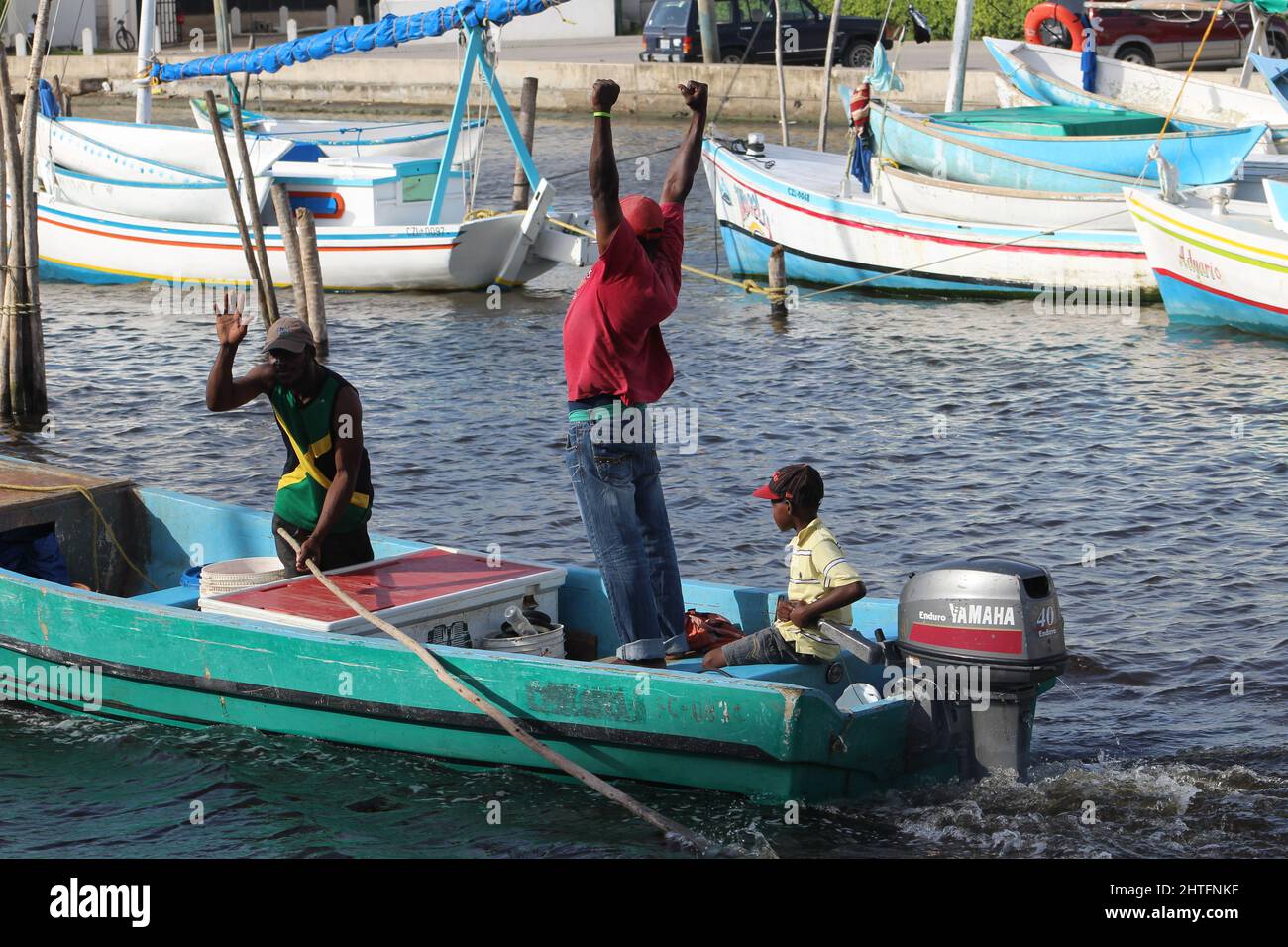 BELIZE CITY, BELIZE - JULY 6, 2016 men and boy at the small fleet of fishing boats moored at the Swing Bridge with fishermen and boats from Sarteneja Stock Photo