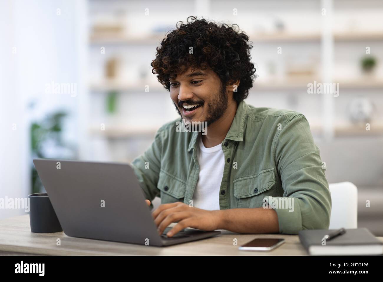 Happy dark-skinned young man using modern laptop Stock Photo