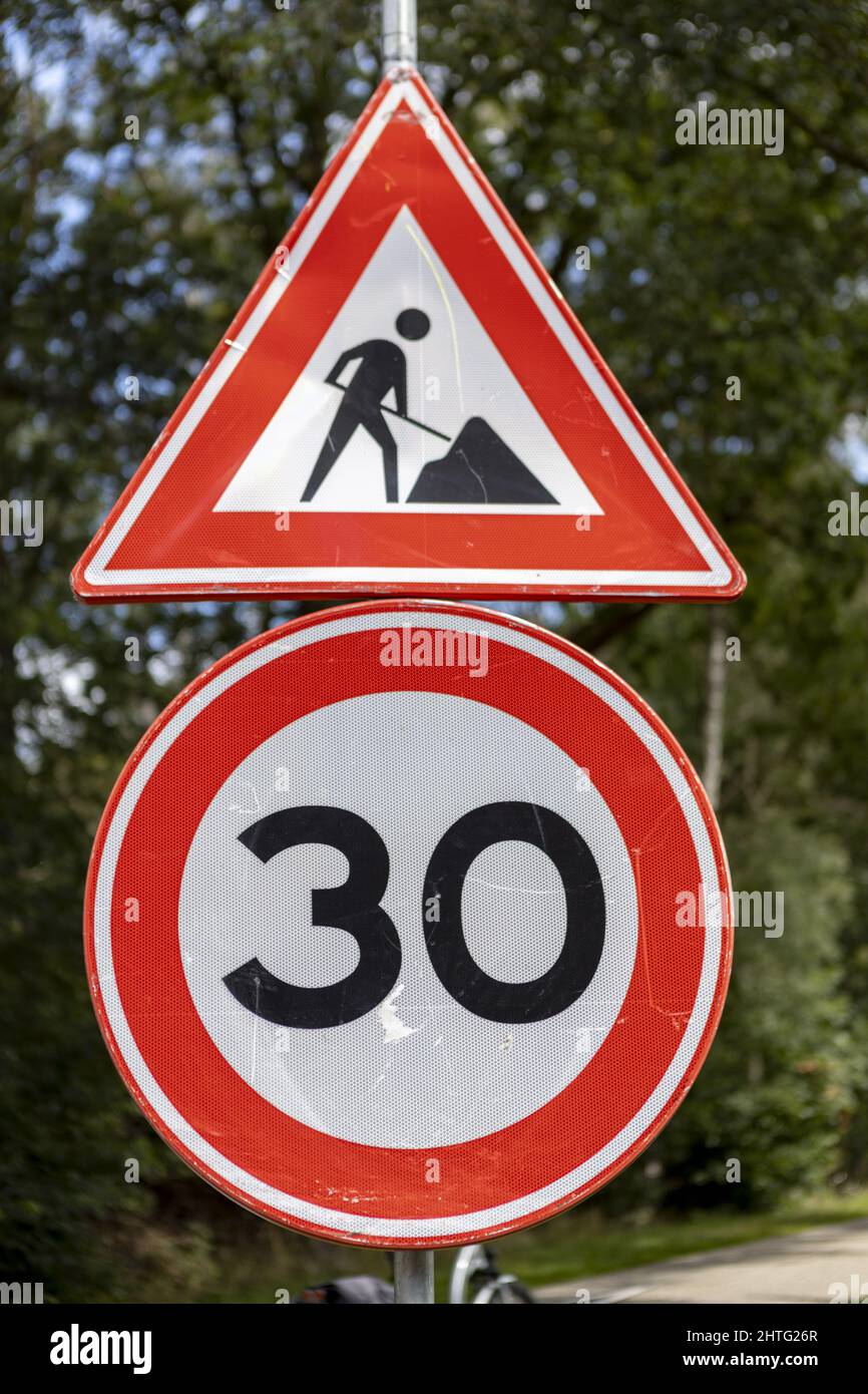 Work in progress and speed limit traffic warning sign on the side of a road Stock Photo