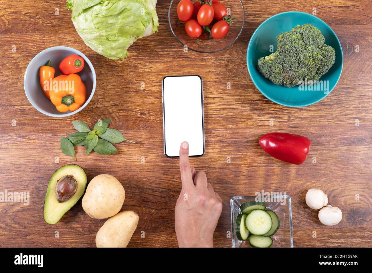 Overhead shot of cropped hand using smart phone amidst various food on table, copy space Stock Photo