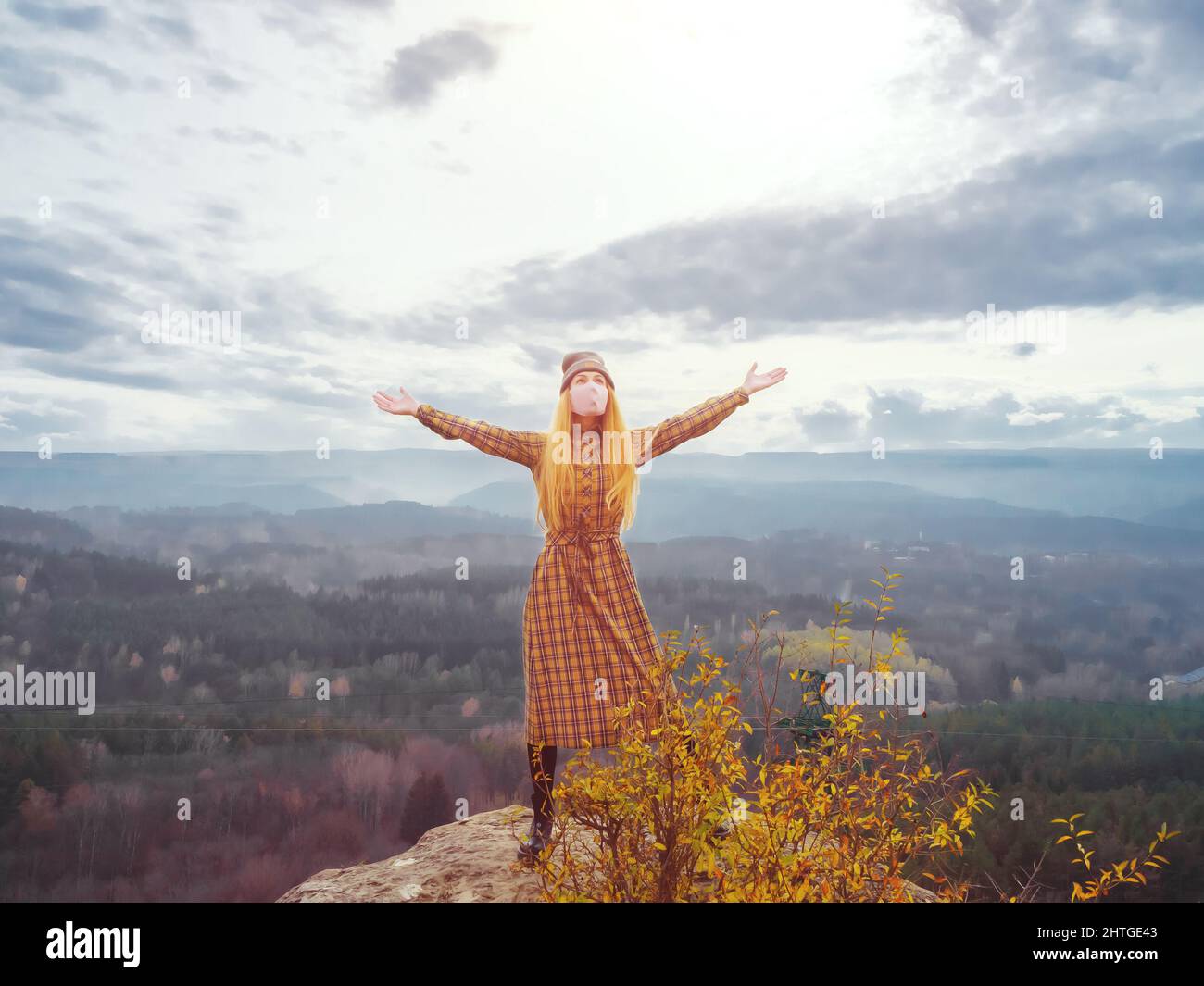 A woman in a dress and face mask stands with her arms outstretched on ...