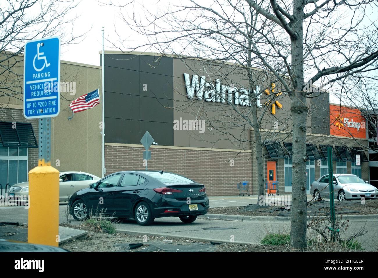 Walmart store with American flag flying at half-mast parking disability sign. Roseville Minnesota MN USA Stock Photo