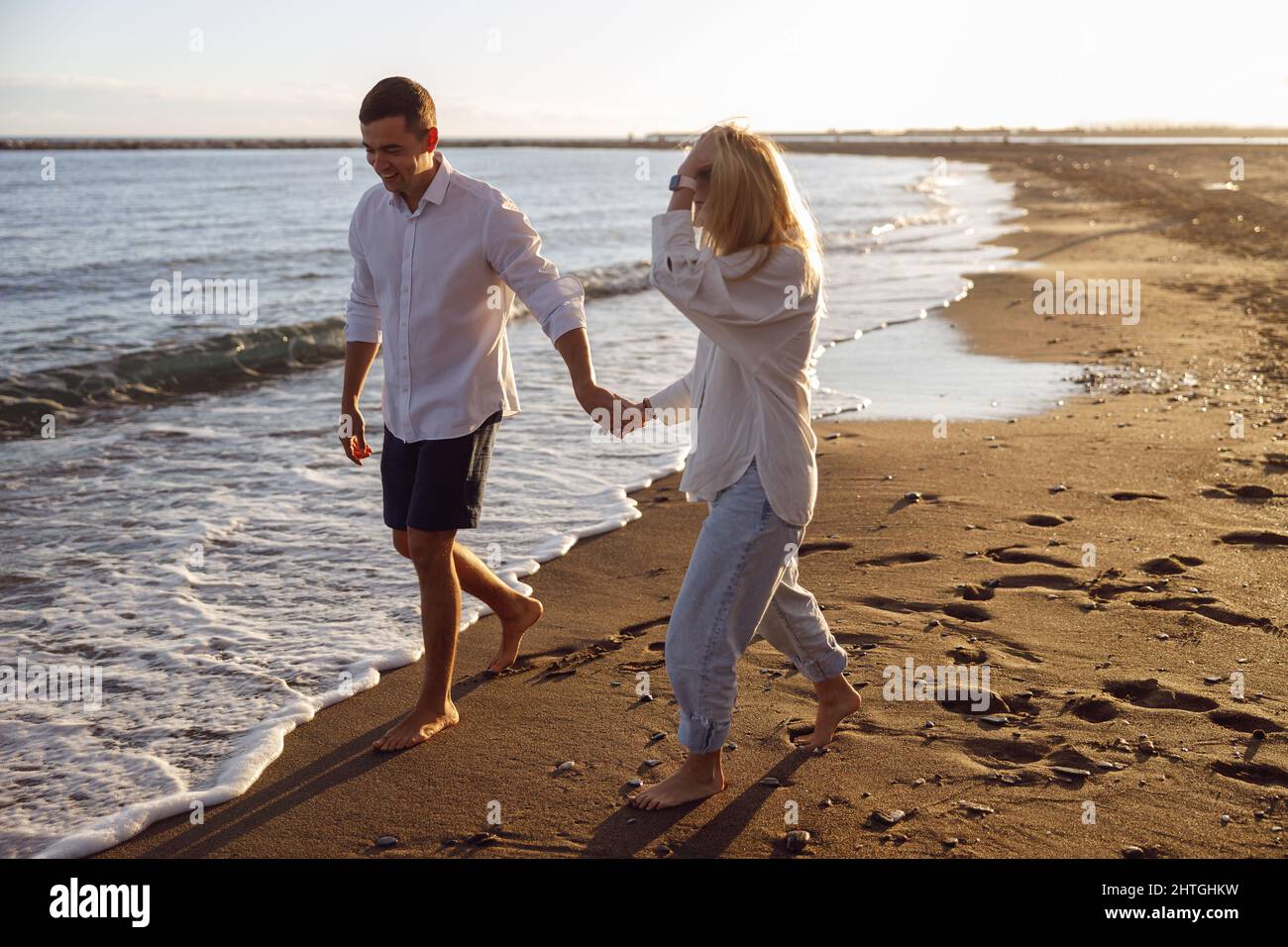 Beautiful couple walking barefoot on the beach holding hands Stock Photo