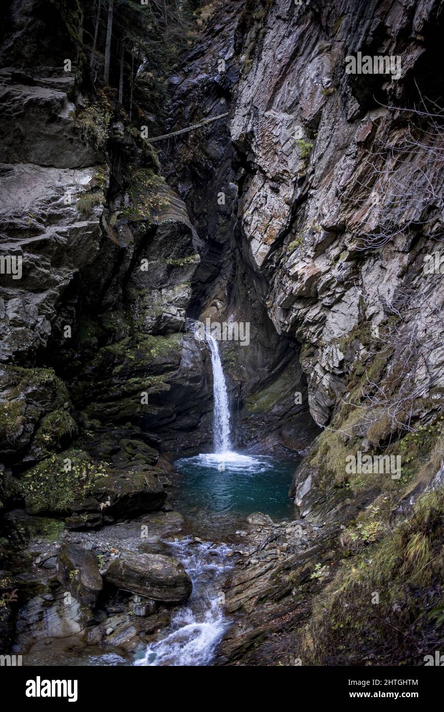 Vertical shot of a waterfall in the forest between rock walls Stock ...