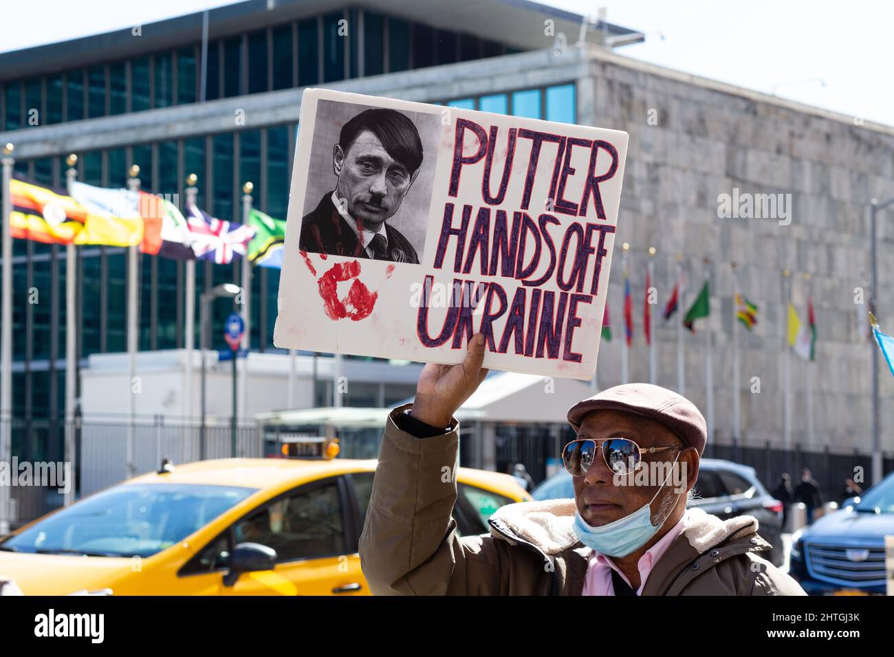 New York, NY, USA. 28th Feb, 2022. Pro-Ukrainian protesters face the United Nations from across First Avenue. A man carries a sign with a photo of Putin with a haircut and mustache like Adolf Hitler's, and which reads “Putler [sic.] Hands Off Ukraine.” Credit: Ed Lefkowicz/Alamy Live News Stock Photo