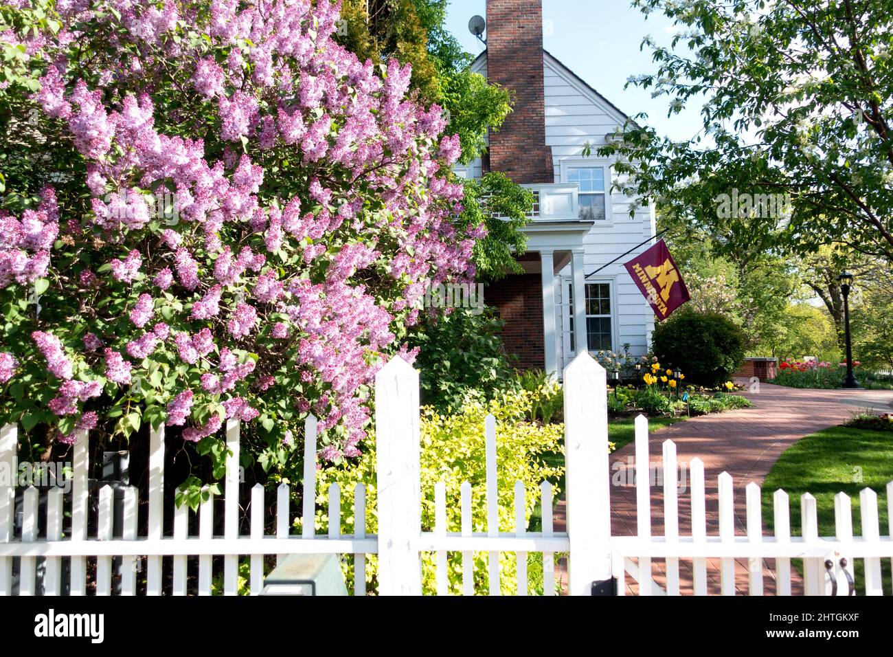 President of the University of Minnesota Eastcliff home with flag, white fence and blooming fruit tree. St Paul Minnesota MN USA Stock Photo