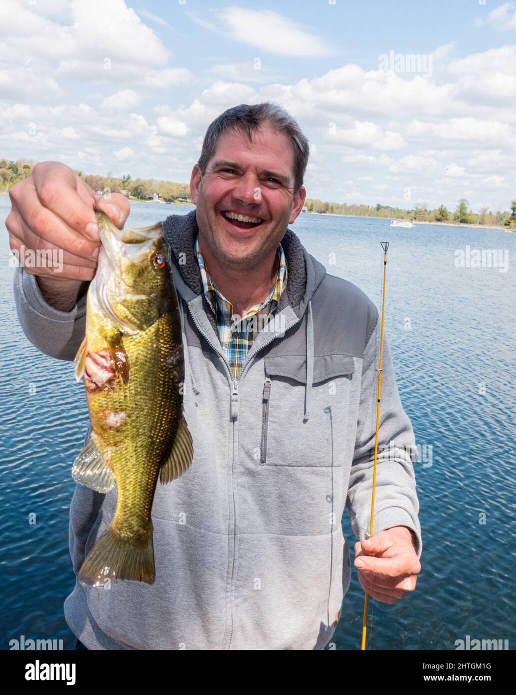 Happy fisherman holding his giant Rock Bass fish close to the camera lens to make it larger. Nisswa Minnesota MN USA Stock Photo